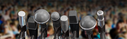 microphones on stage overlooking audience at speaking event